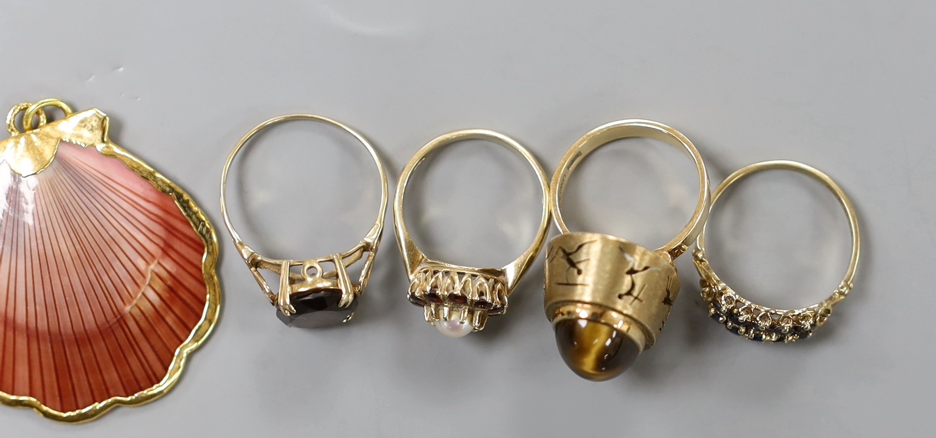 Eight assorted modern 9ct gold and gem set dress rings, a pair of 9ct and carnelian set drop earrings, gross weight 30.7 grams. and a yellow metal mounted shell pendant.